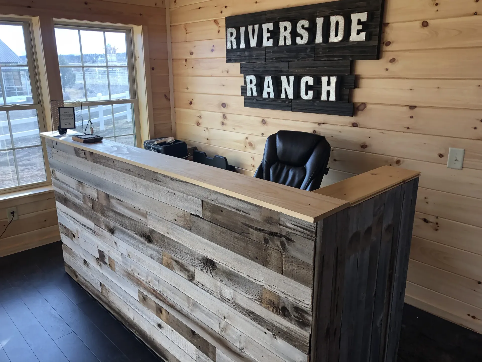 A wooden reception desk with a sign above it that says riverside ranch.