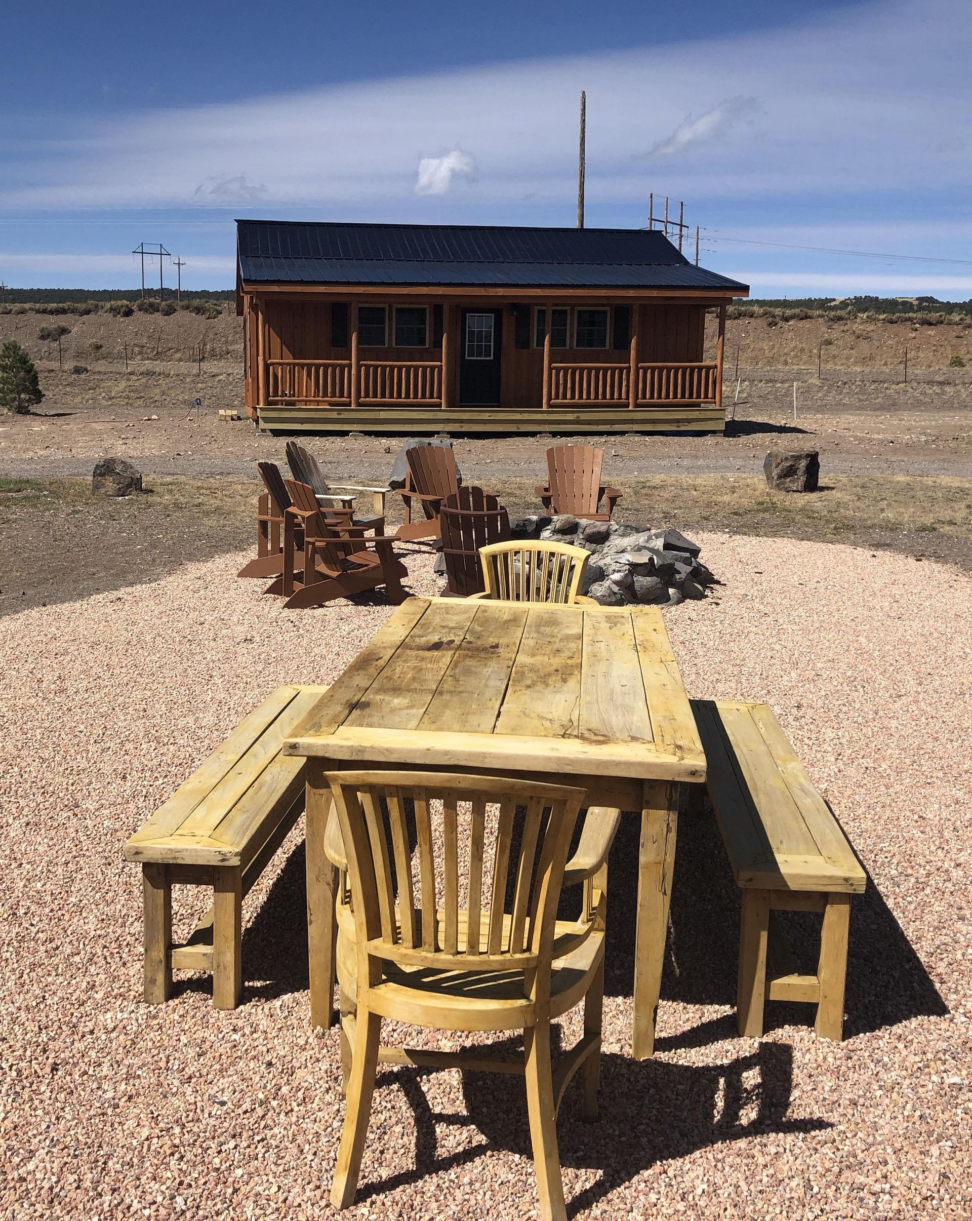 A wooden table and chairs are sitting in front of a small house.