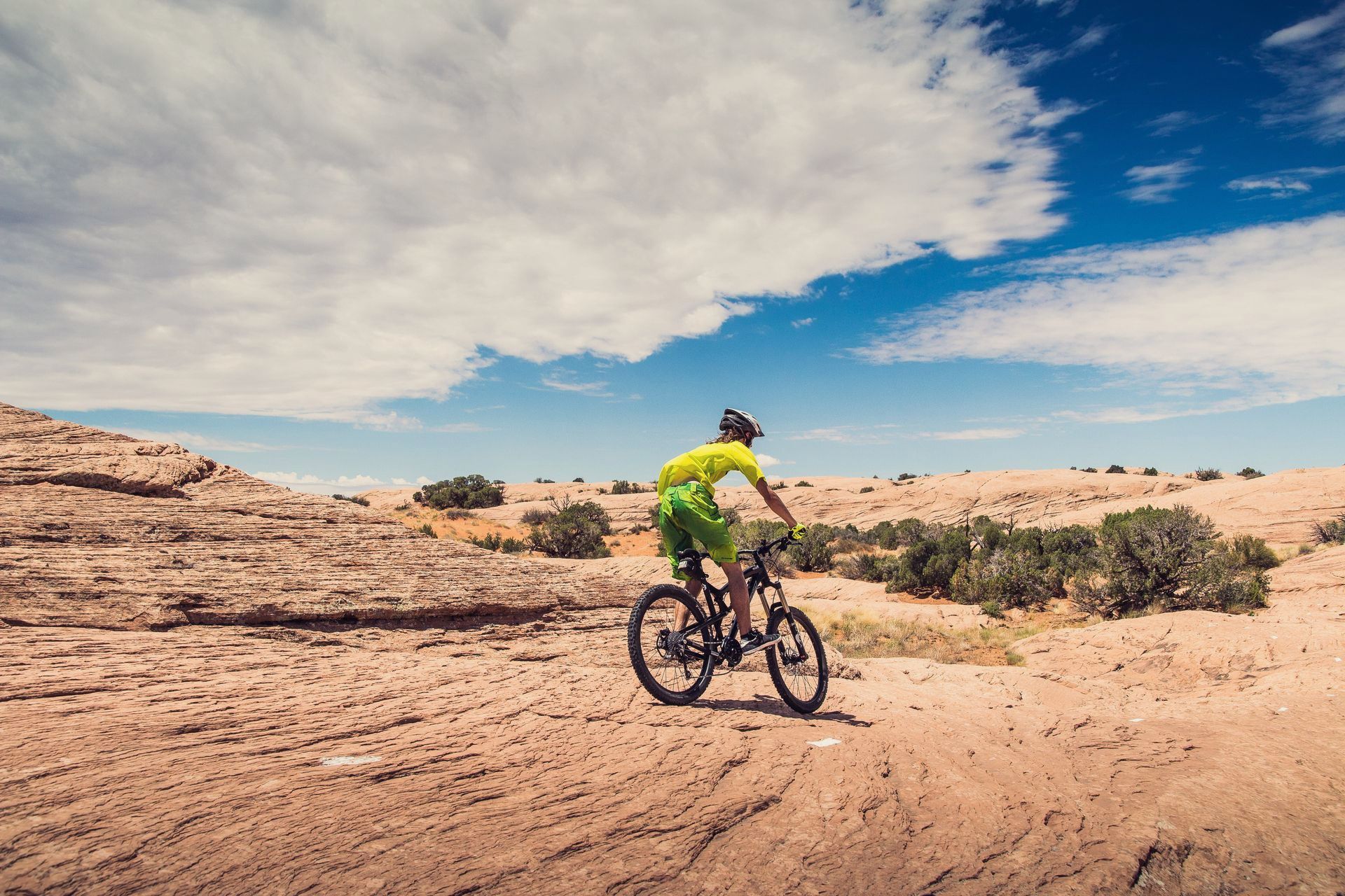 A person is riding a bike on a dirt road in the desert.