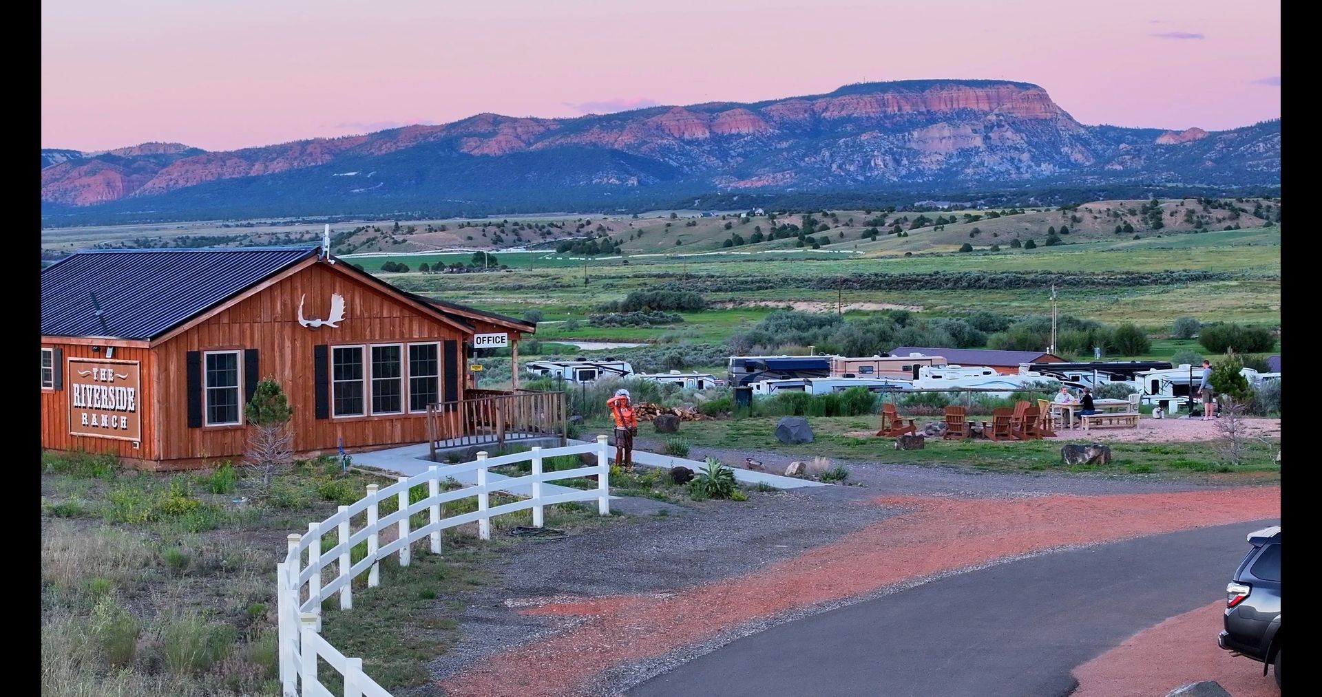 A house with a white fence and mountains in the background