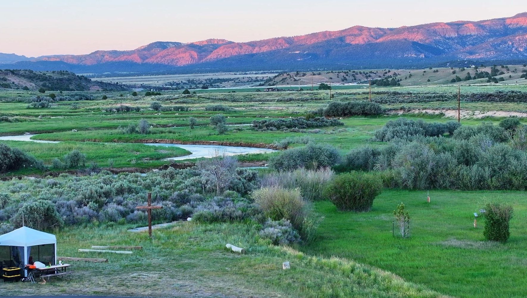 A rv is parked in a grassy field with mountains in the background.