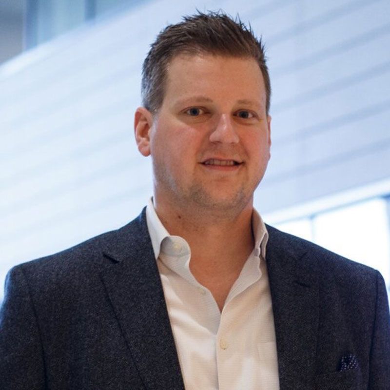 A man in a suit and white shirt is smiling for the camera.