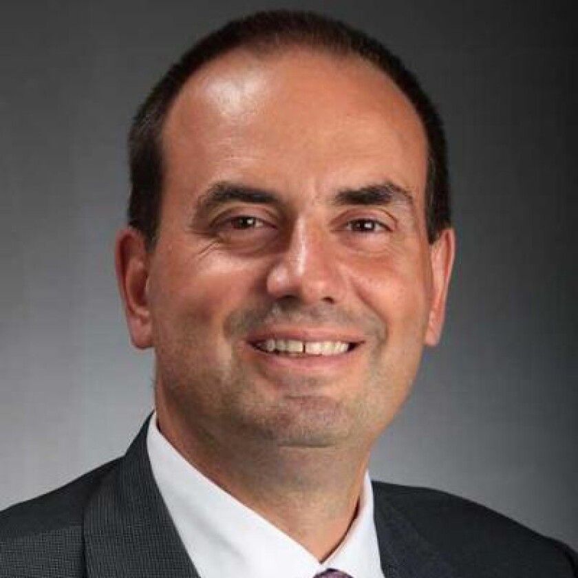 A man in a suit and tie is smiling for the camera.