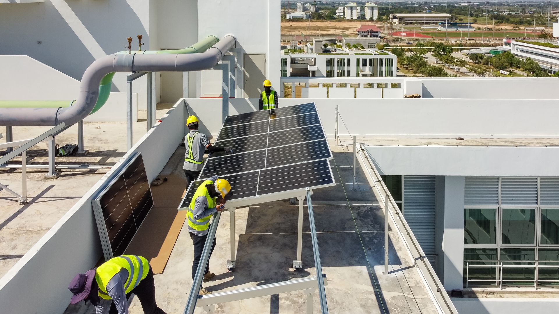 A group of construction workers are installing solar panels on the roof of a building.