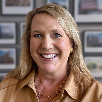 A woman is smiling for the camera in front of a wall of pictures.