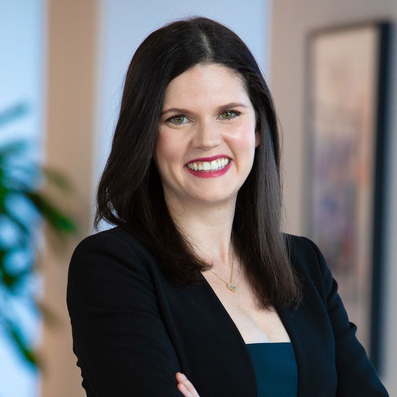 A woman in a black jacket is smiling for the camera.