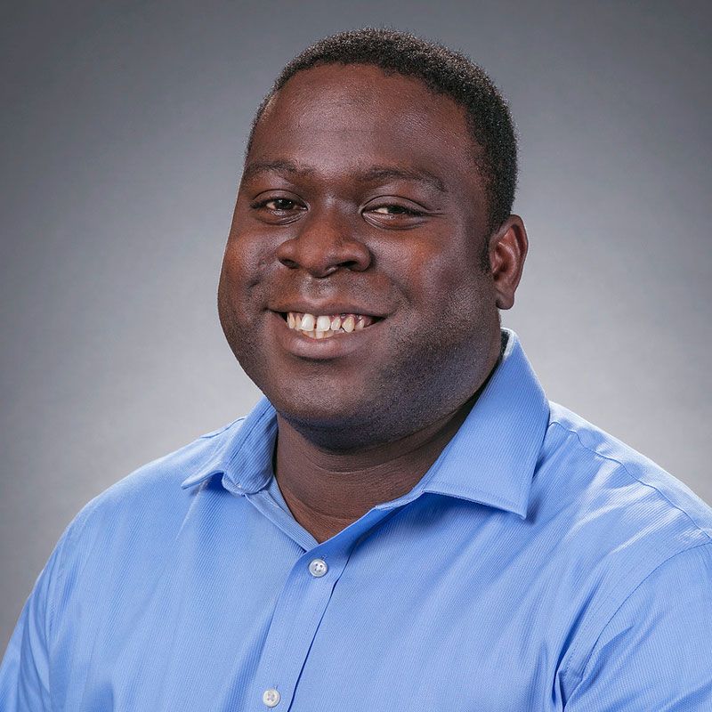 A man in a blue shirt is smiling for the camera.