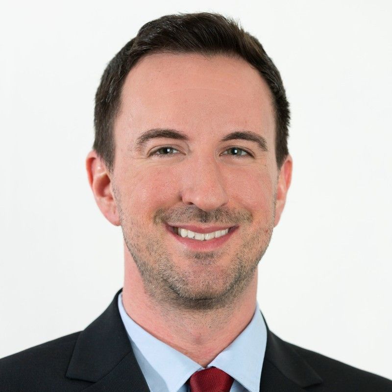 A man in a suit and tie is smiling for the camera