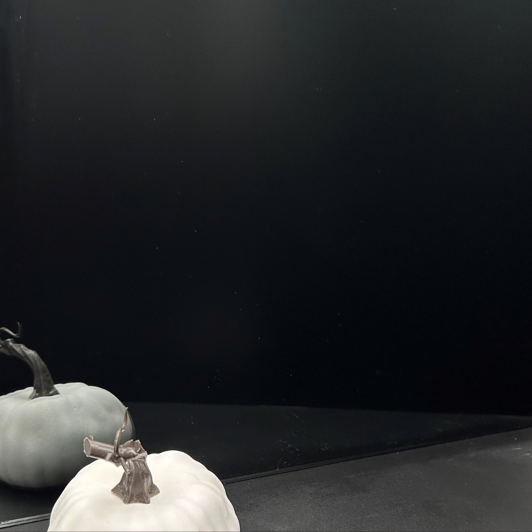 Two white pumpkins are sitting on a table in front of a black background.