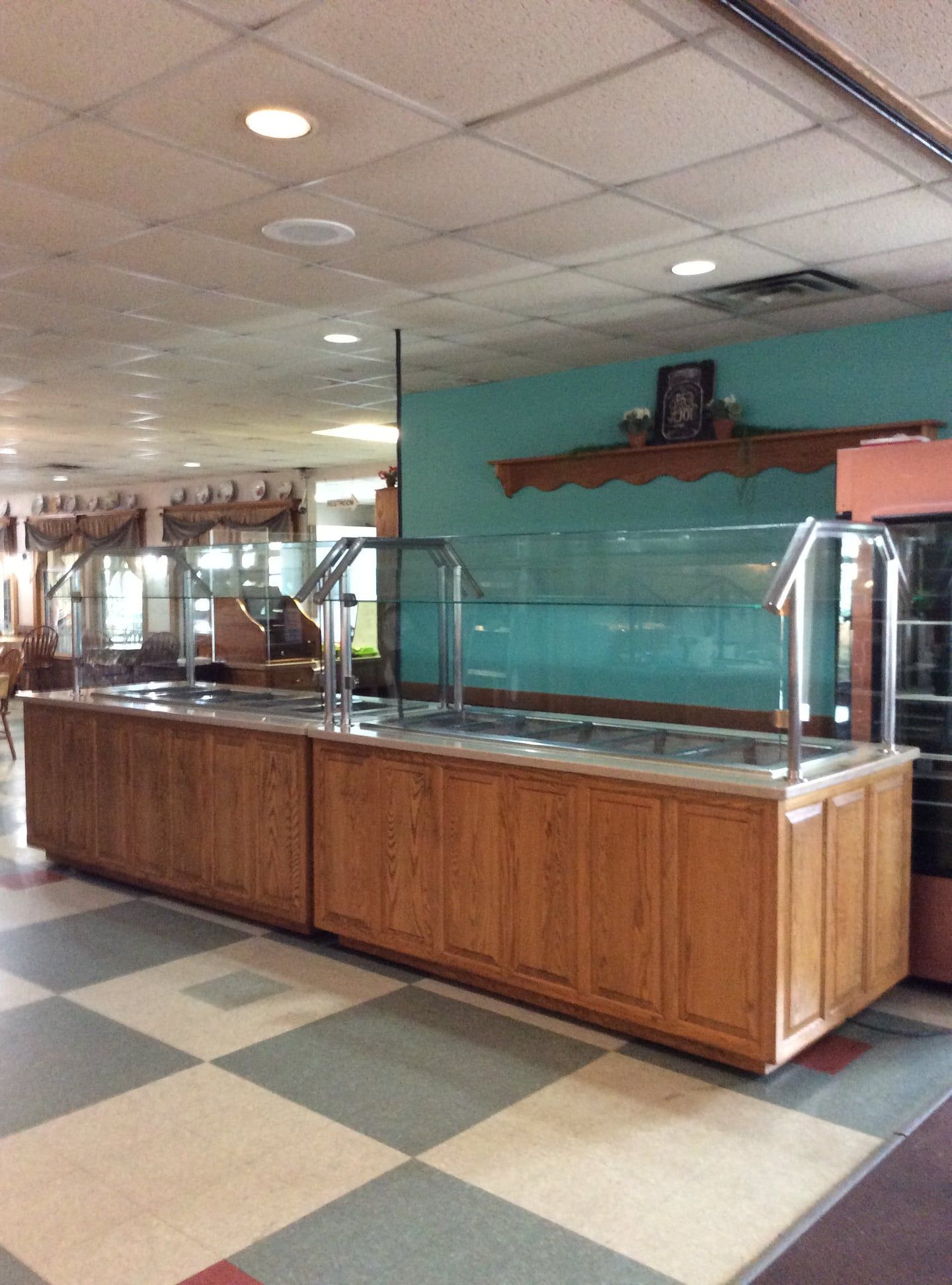 A long wooden buffet line in a restaurant with a checkered floor.