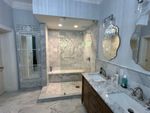 A bathroom with a walk in shower , sink and mirrors.