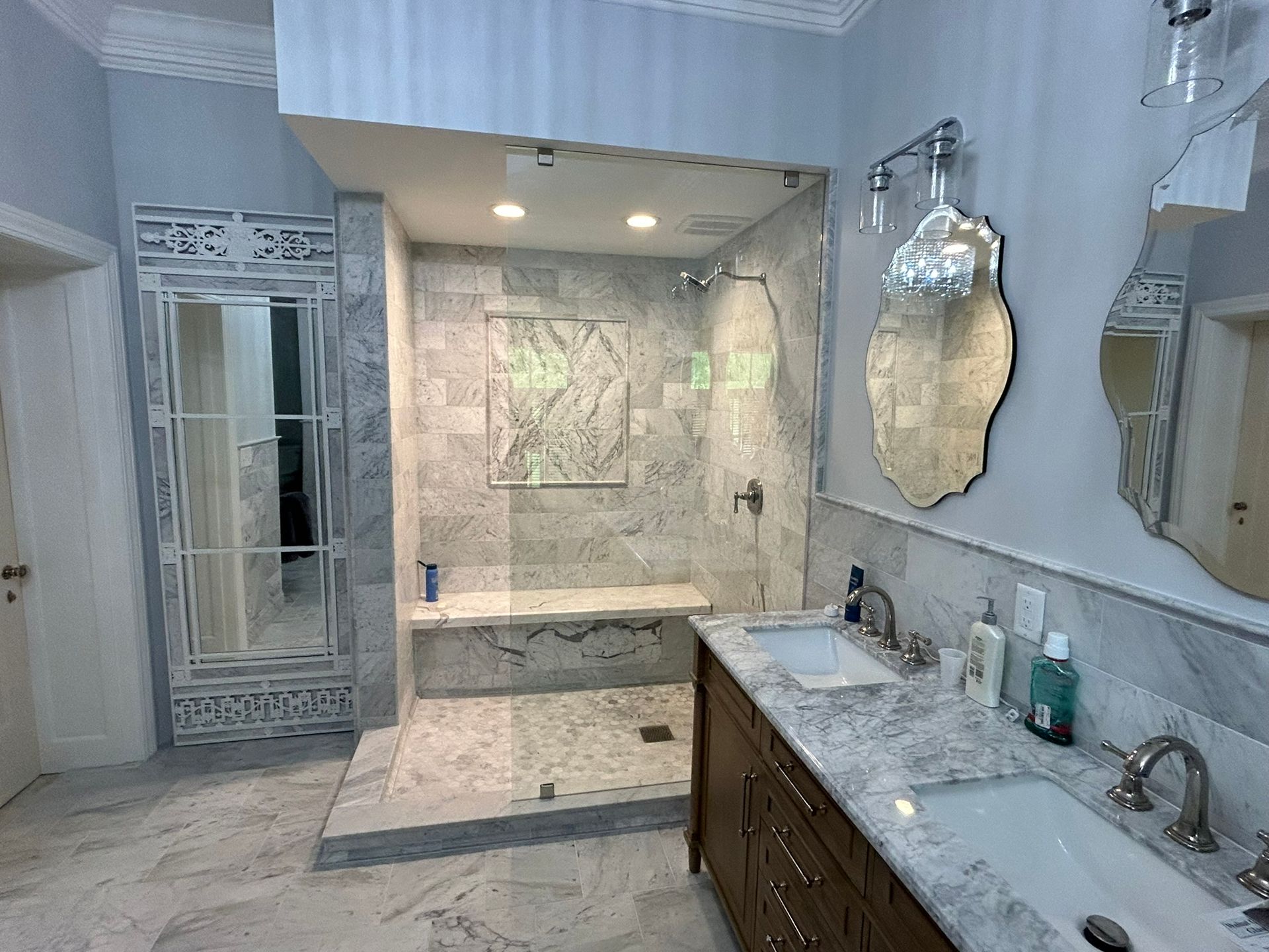 A bathroom with a walk in shower , sink and mirrors.