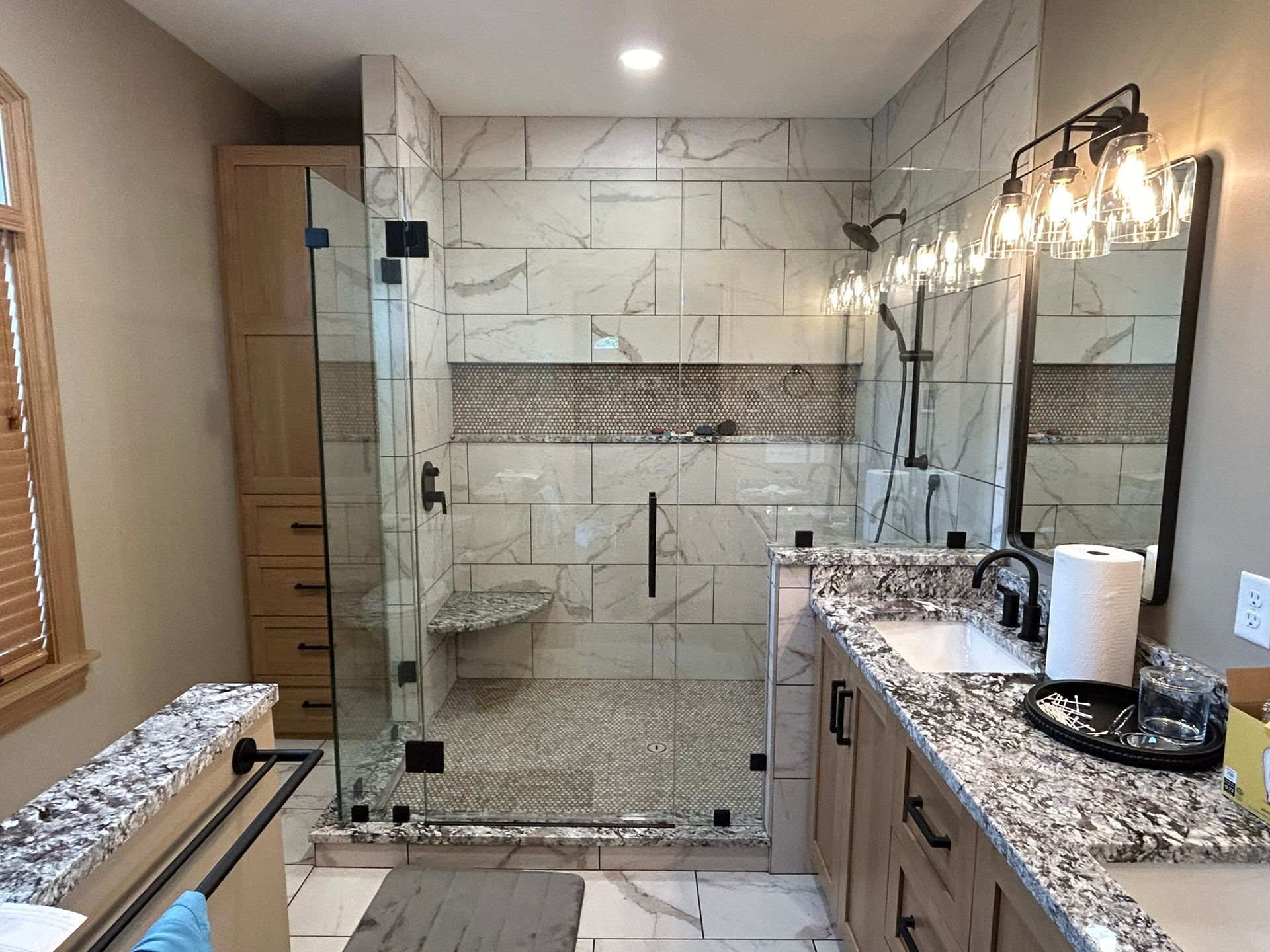 A bathroom with a walk in shower , sink and mirror.