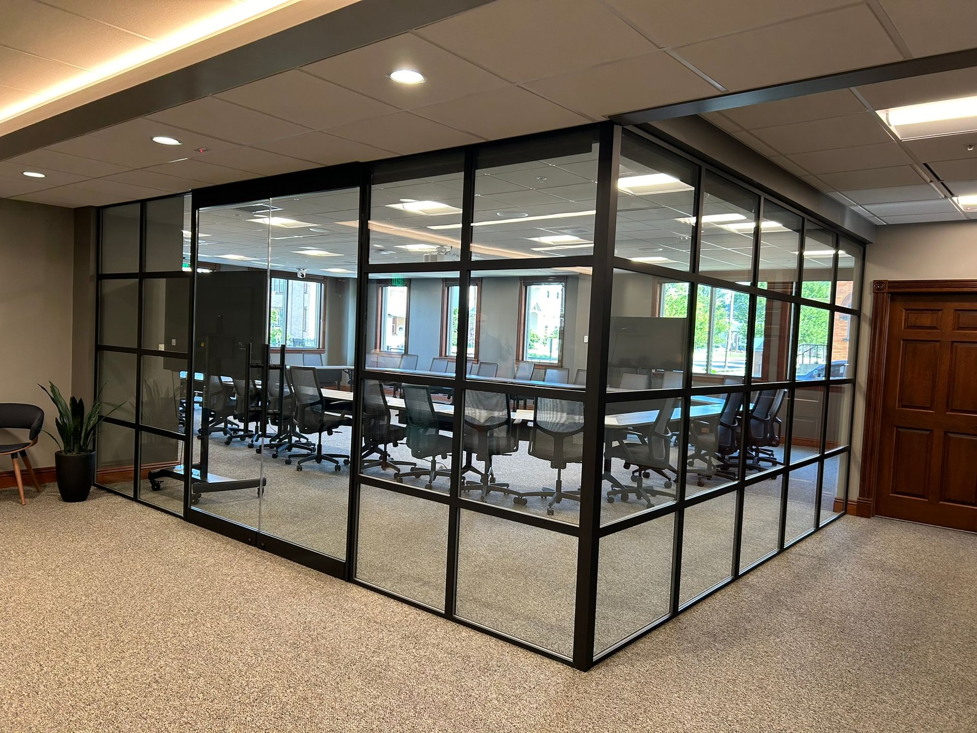 A conference room with tables and chairs and a glass wall.