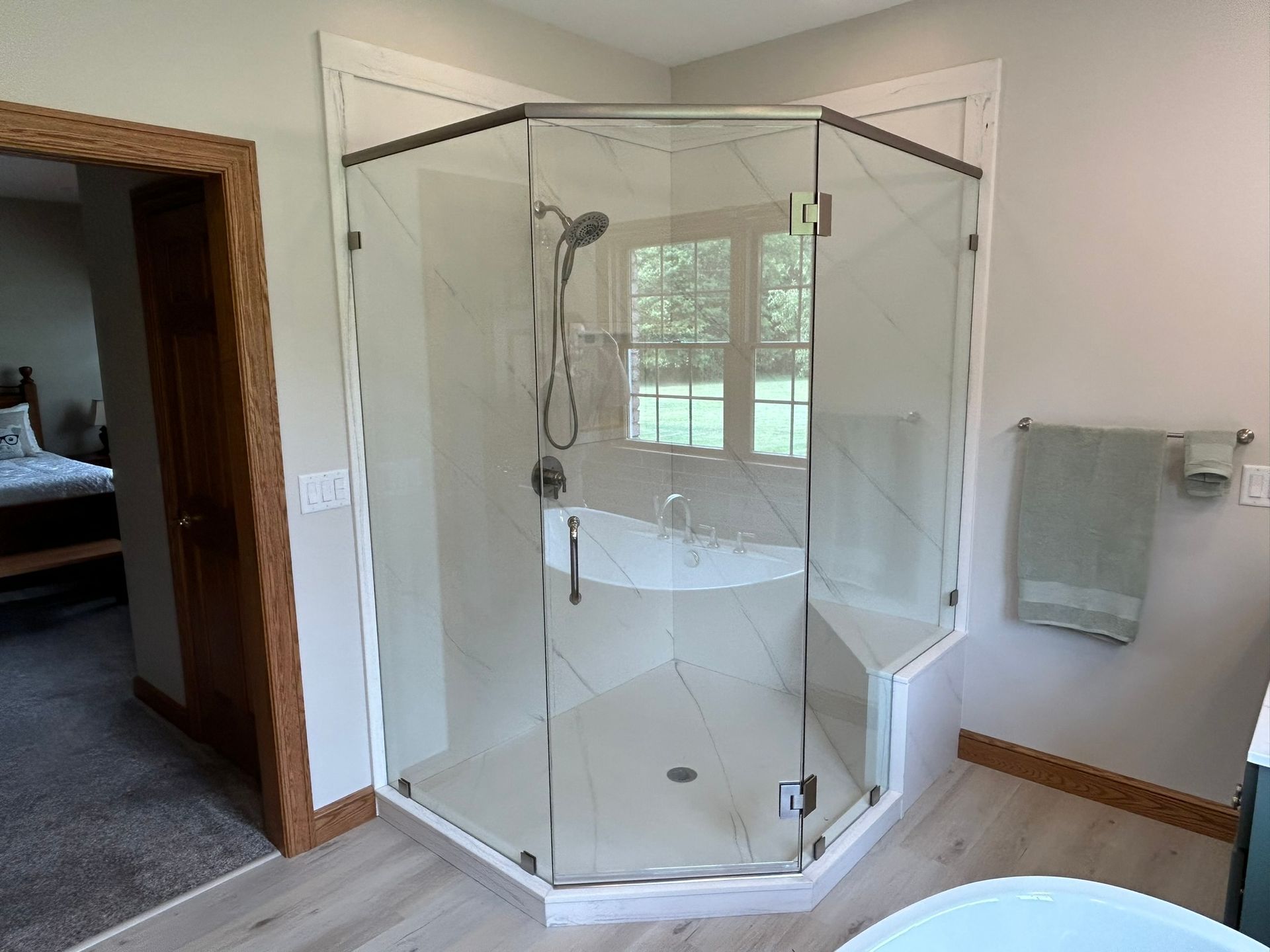 A bathroom with a walk in shower and a tub.