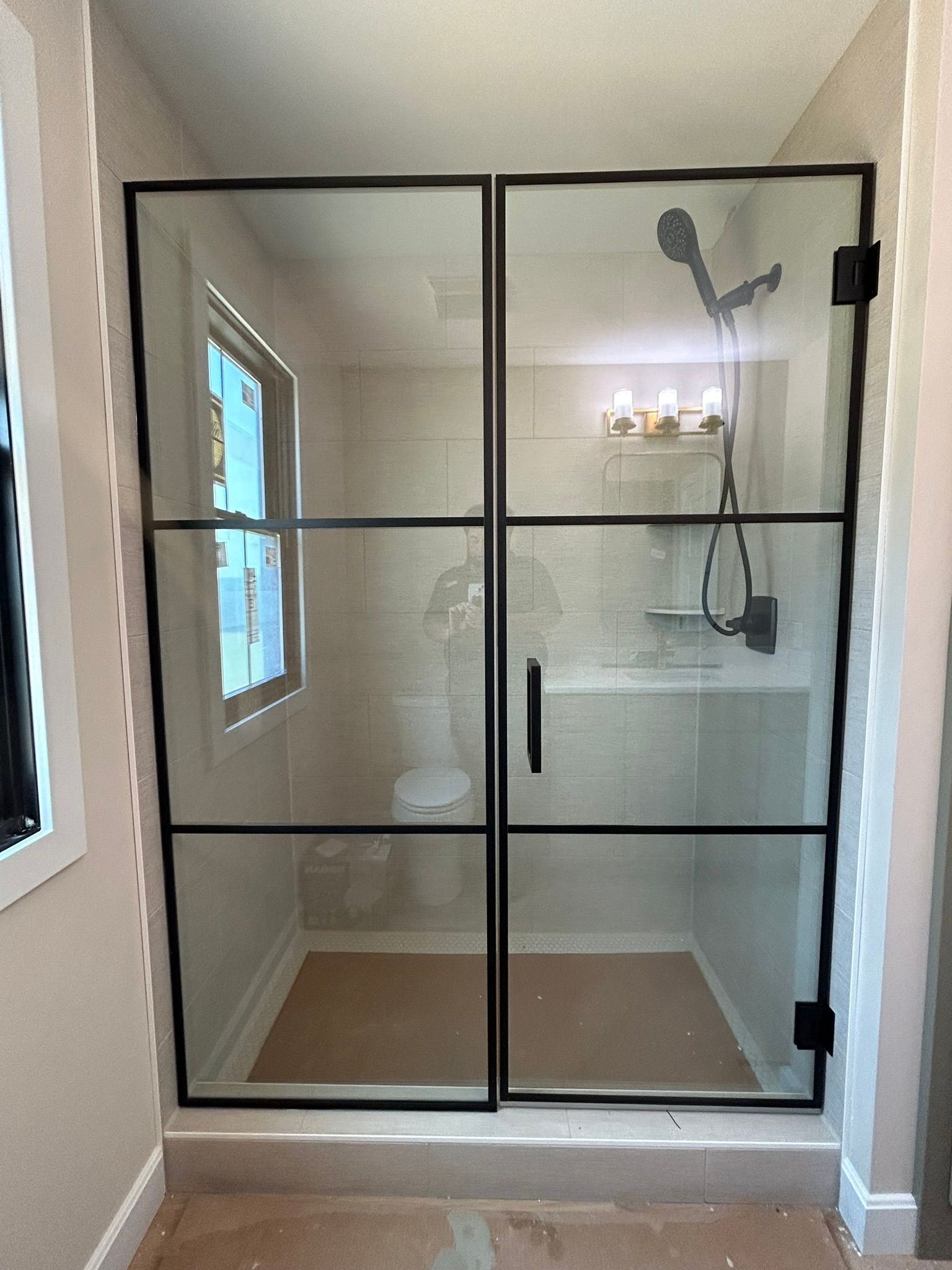 A bathroom with a walk in shower with a black frame.