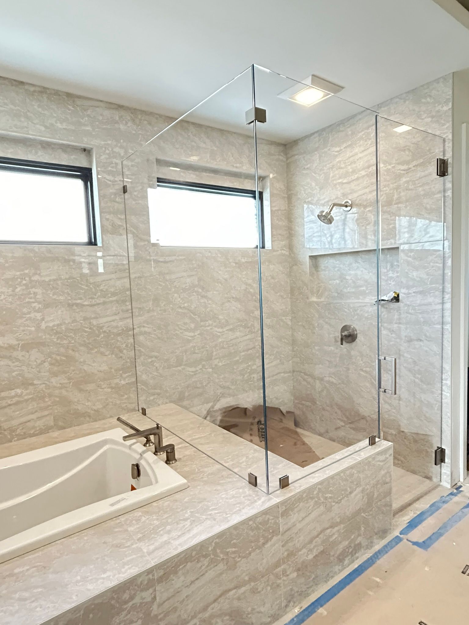 A bathroom with a tub and a shower with a glass door.