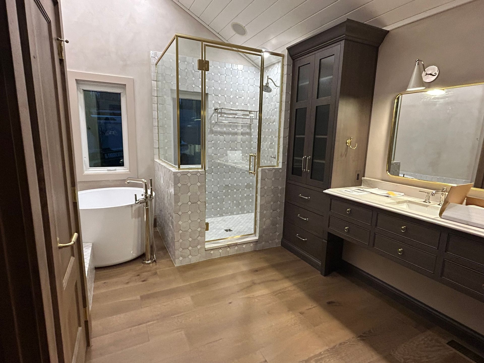 A bathroom with a tub , sink , shower and mirror.