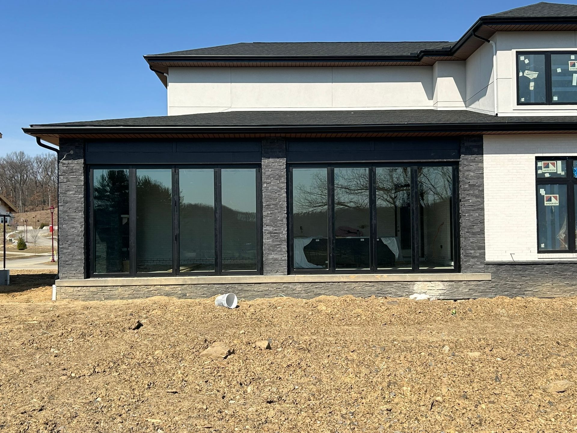 A large house with a lot of windows is sitting on top of a dirt field.