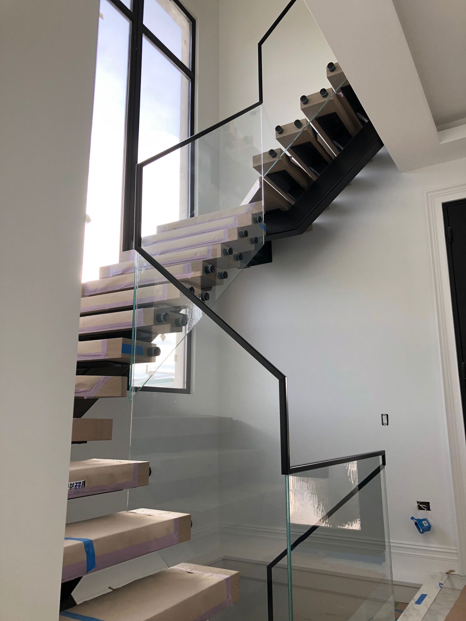 A staircase with a glass railing is being built in a house