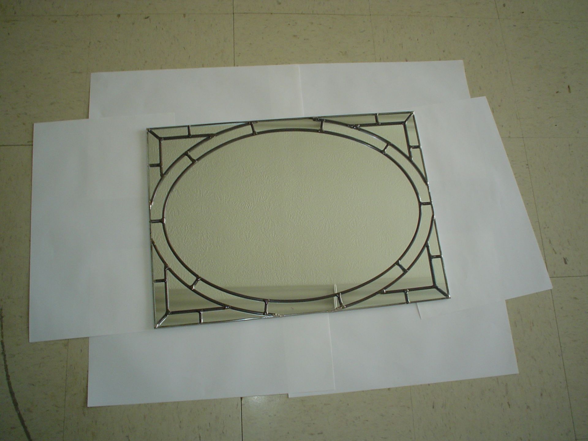 A stained glass mirror is laying on a piece of paper