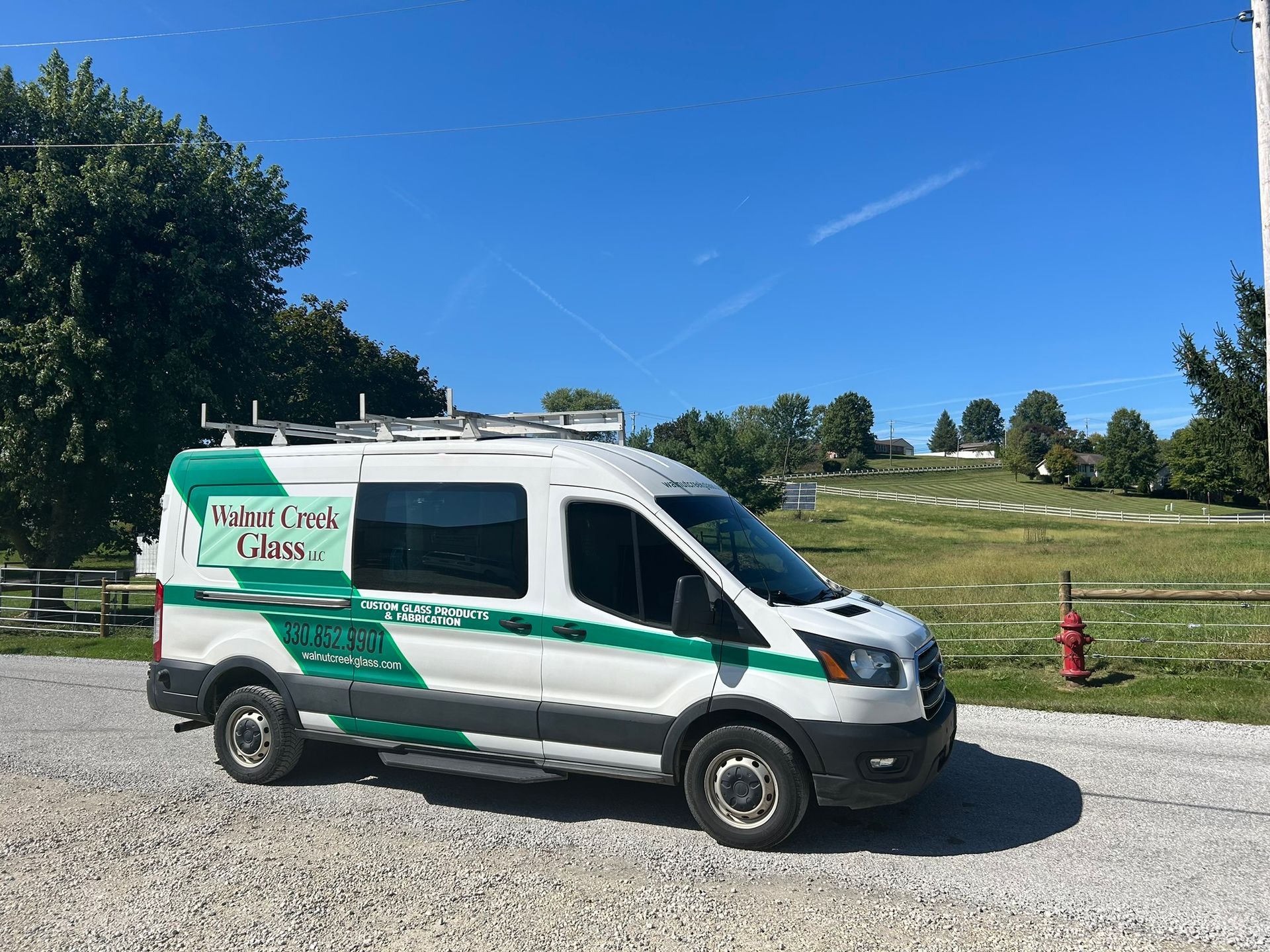 A white and green van is parked in a gravel lot.