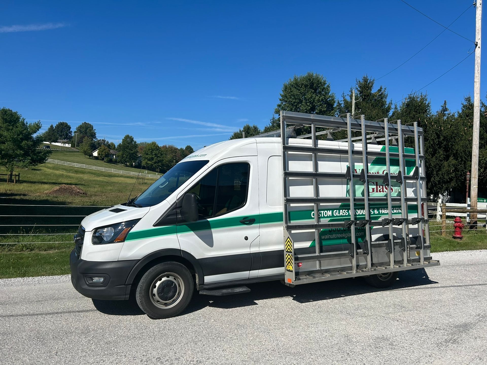 A white van with a glass rack on the back is parked on the side of the road.