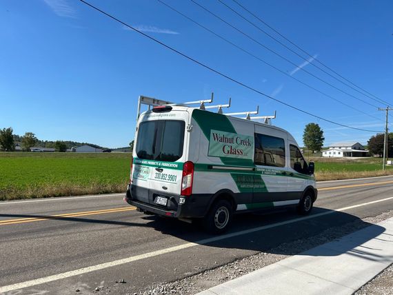 A white and green van is driving down a road.