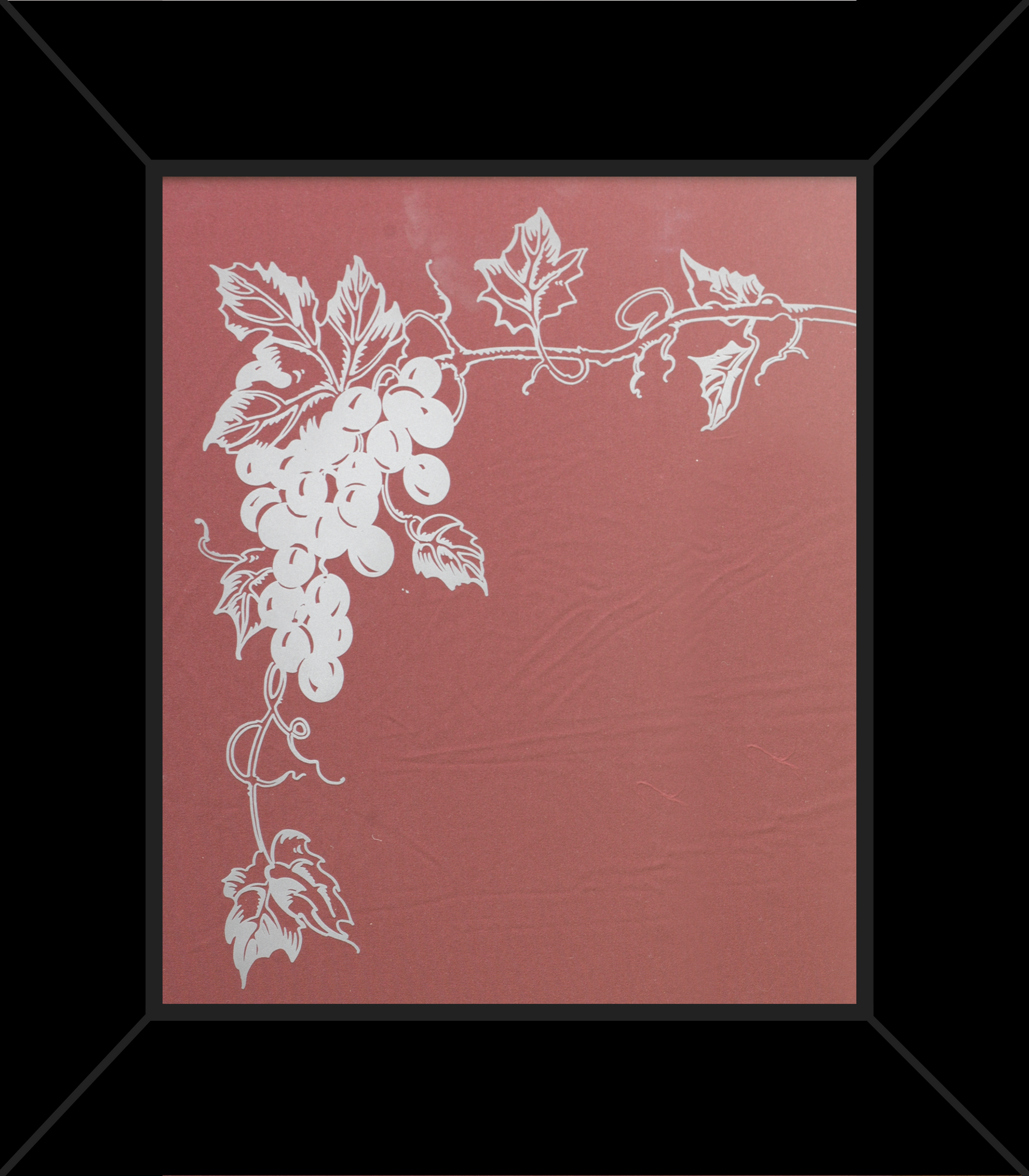 A framed picture of grapes and leaves on a red background