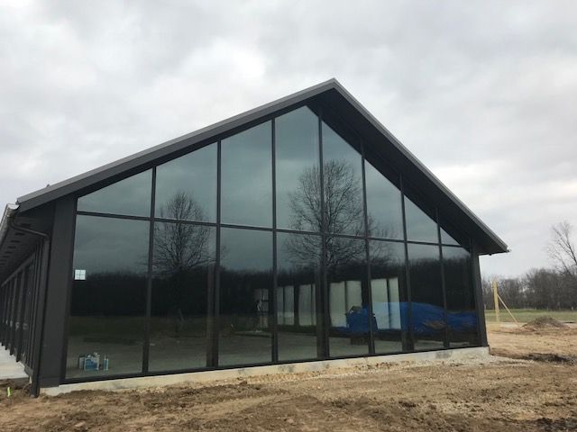 A large building with a lot of windows is sitting in the middle of a field.