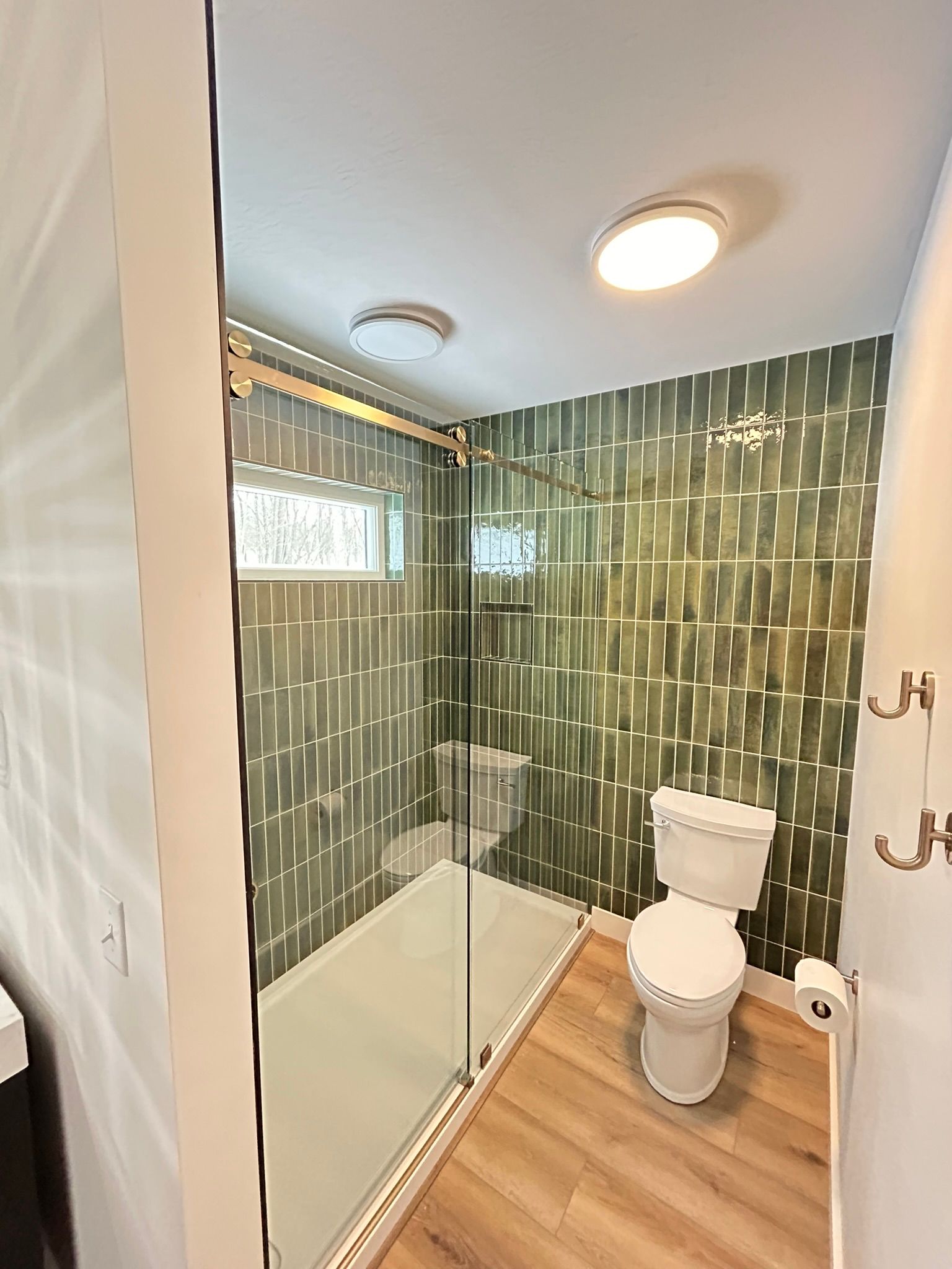 A bathroom with a toilet and a shower stall with sliding glass doors.