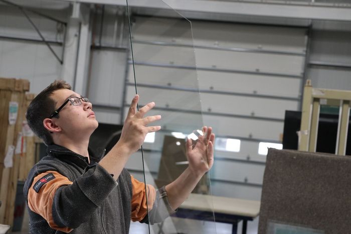 A man is working on a piece of glass in a factory.