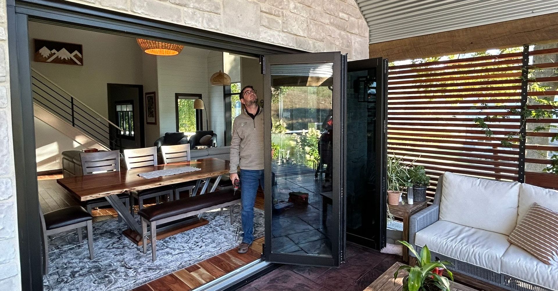 A man is standing in front of a sliding glass door in a living room.