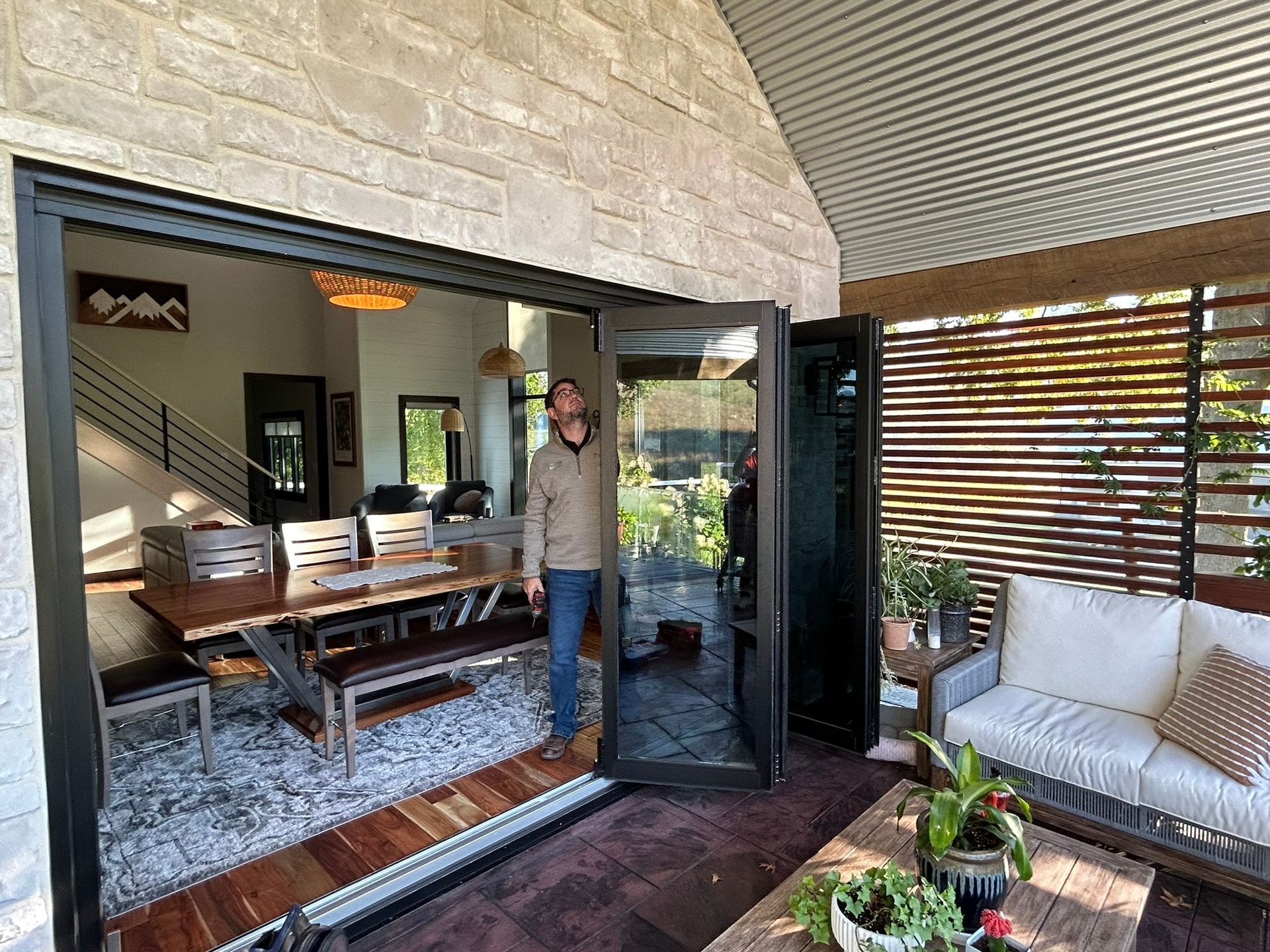 A man is standing in front of a sliding glass door in a living room.