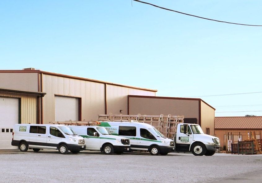 Three white vans are parked in front of a building