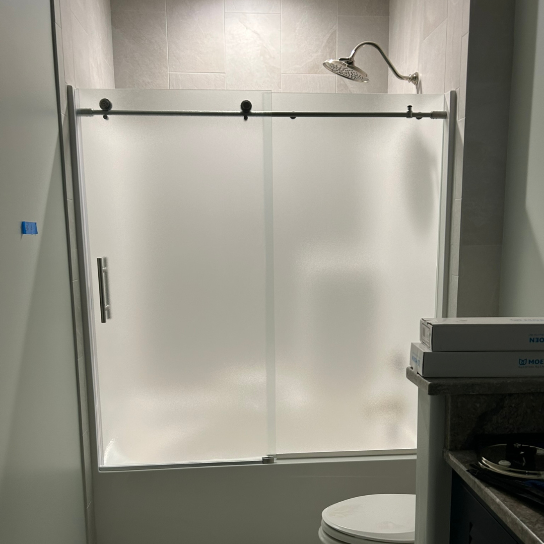 A bathroom with a sliding glass shower door and a toilet.