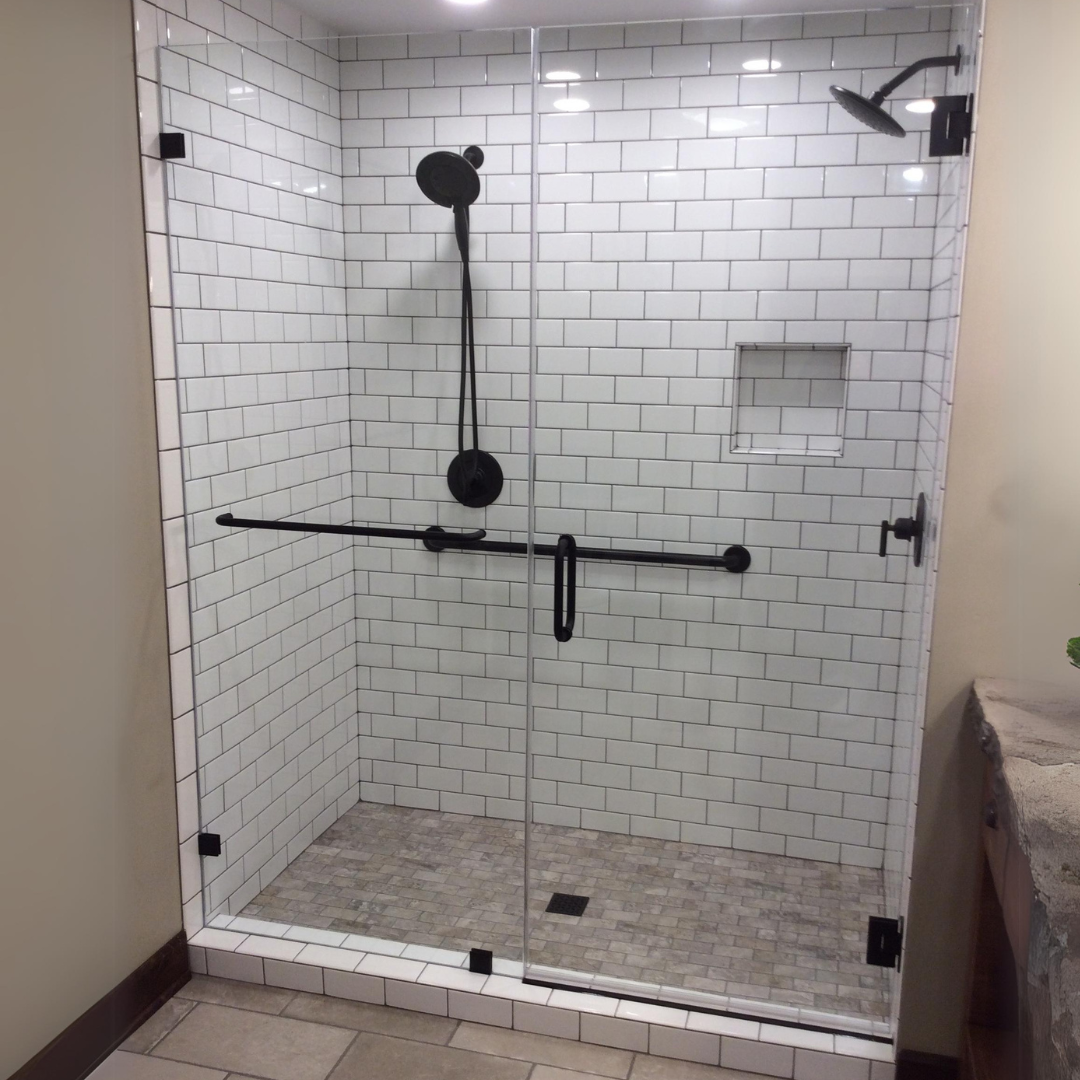 A bathroom with white brick walls and a walk in shower with a glass door.