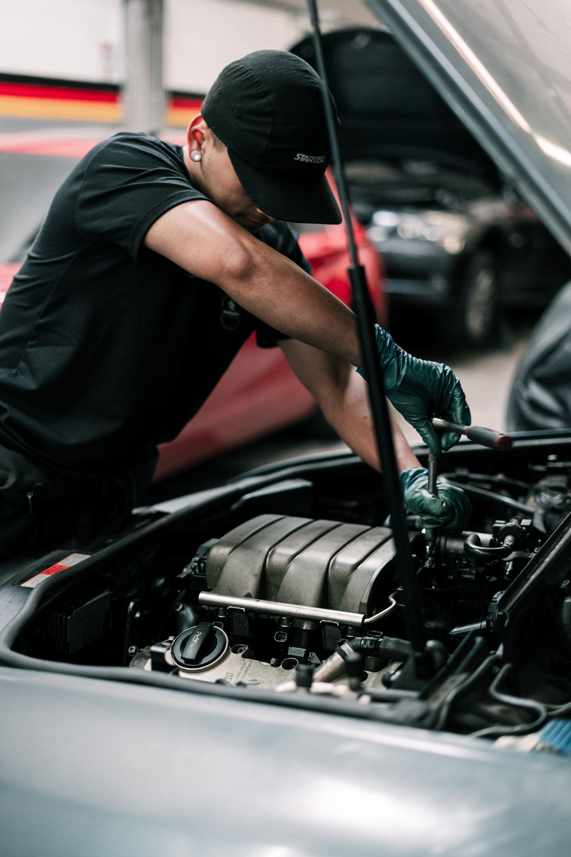 A man is working on the engine of a car with the hood open.