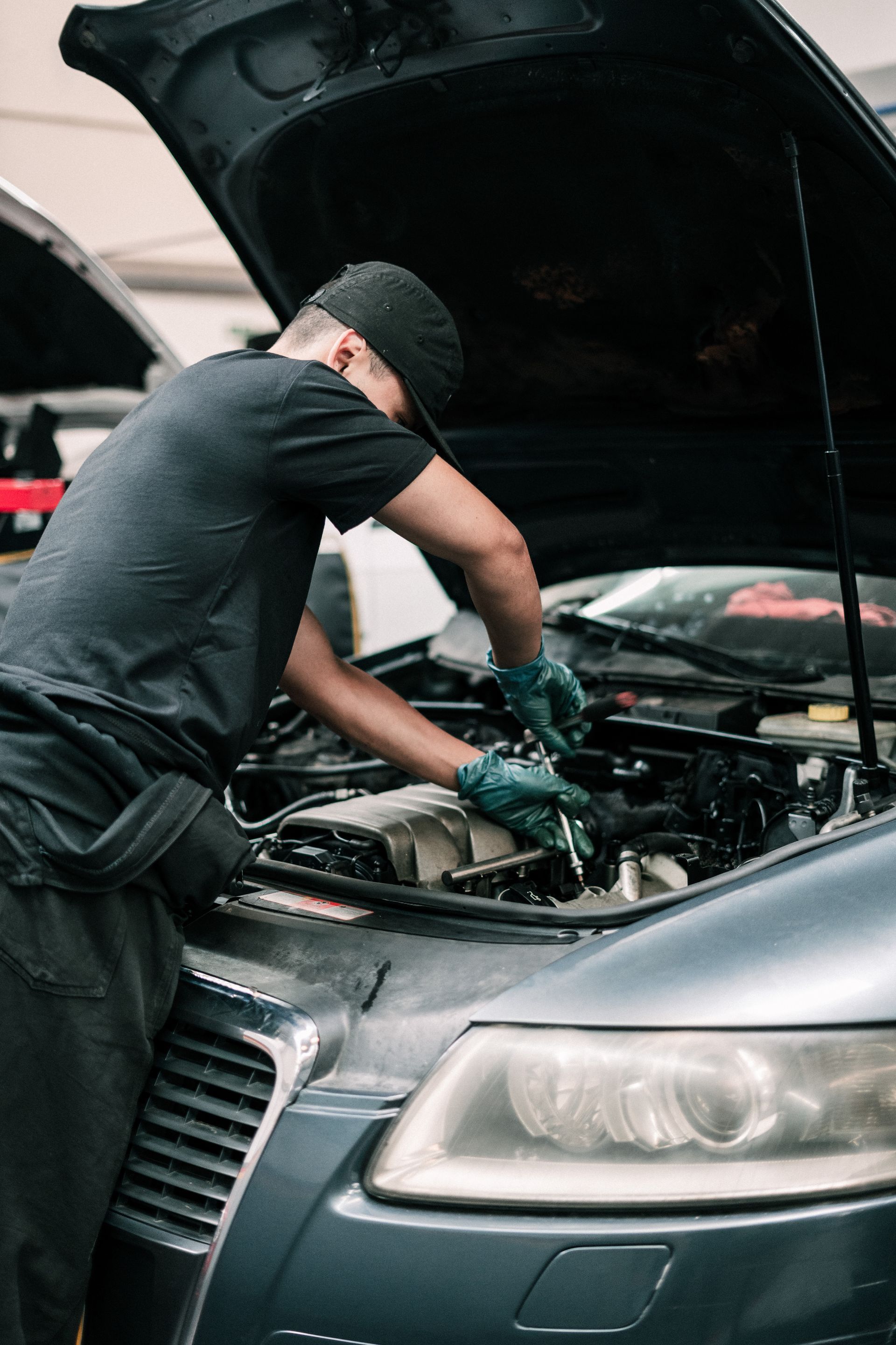 A man is working on the engine of a car with the hood open.