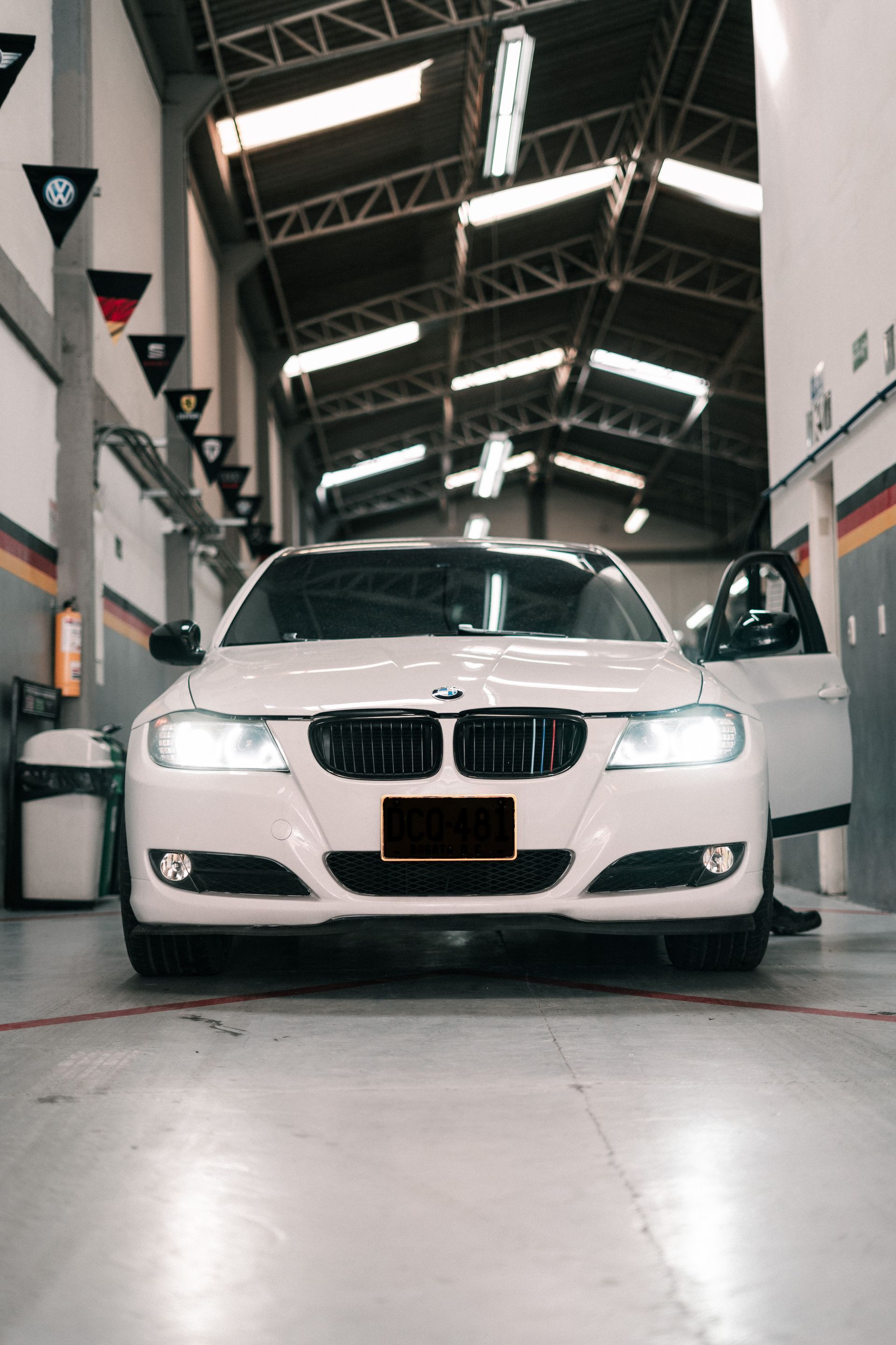 A white bmw is parked in a garage with its doors open.