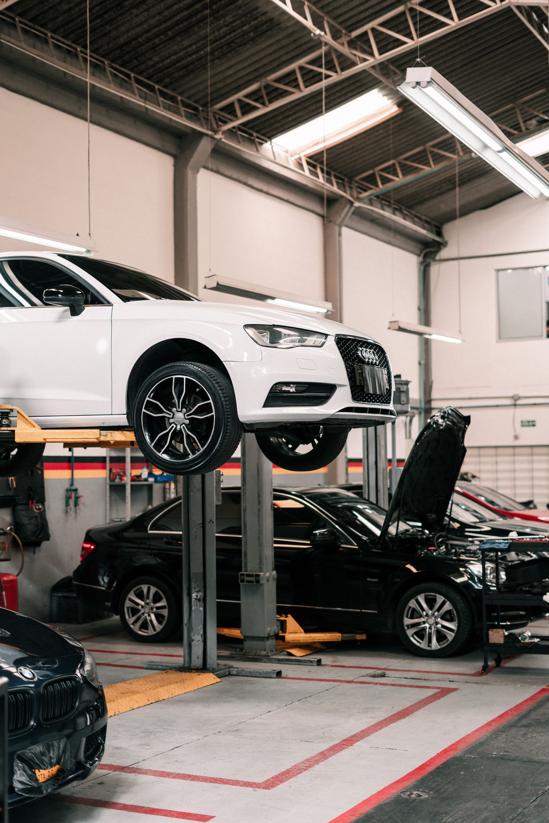 A white car is sitting on a lift in a garage.