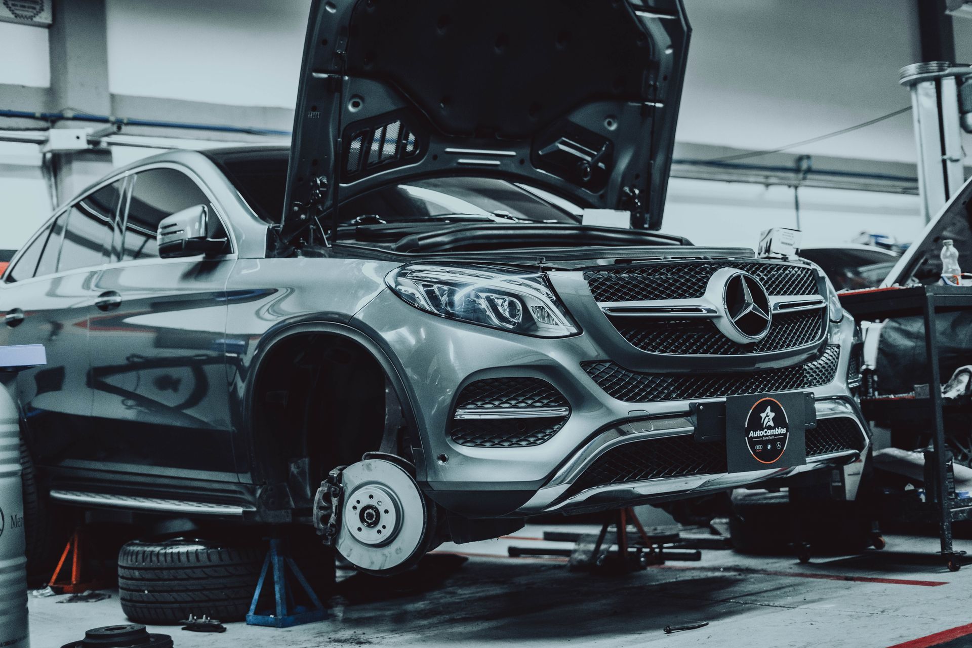A mercedes benz gle is being repaired in a garage with the hood open.