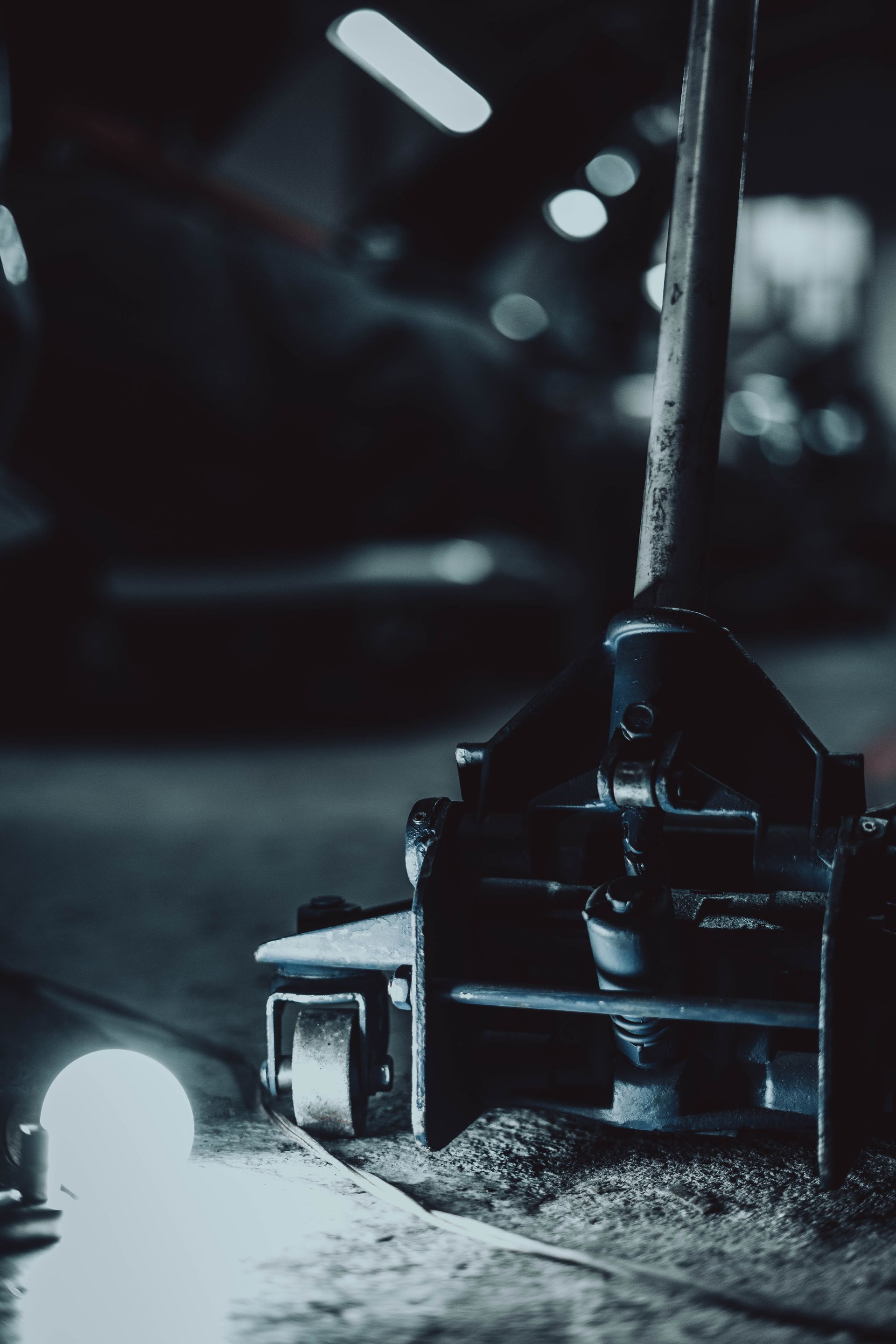 A car jack is sitting on the ground next to a light bulb.