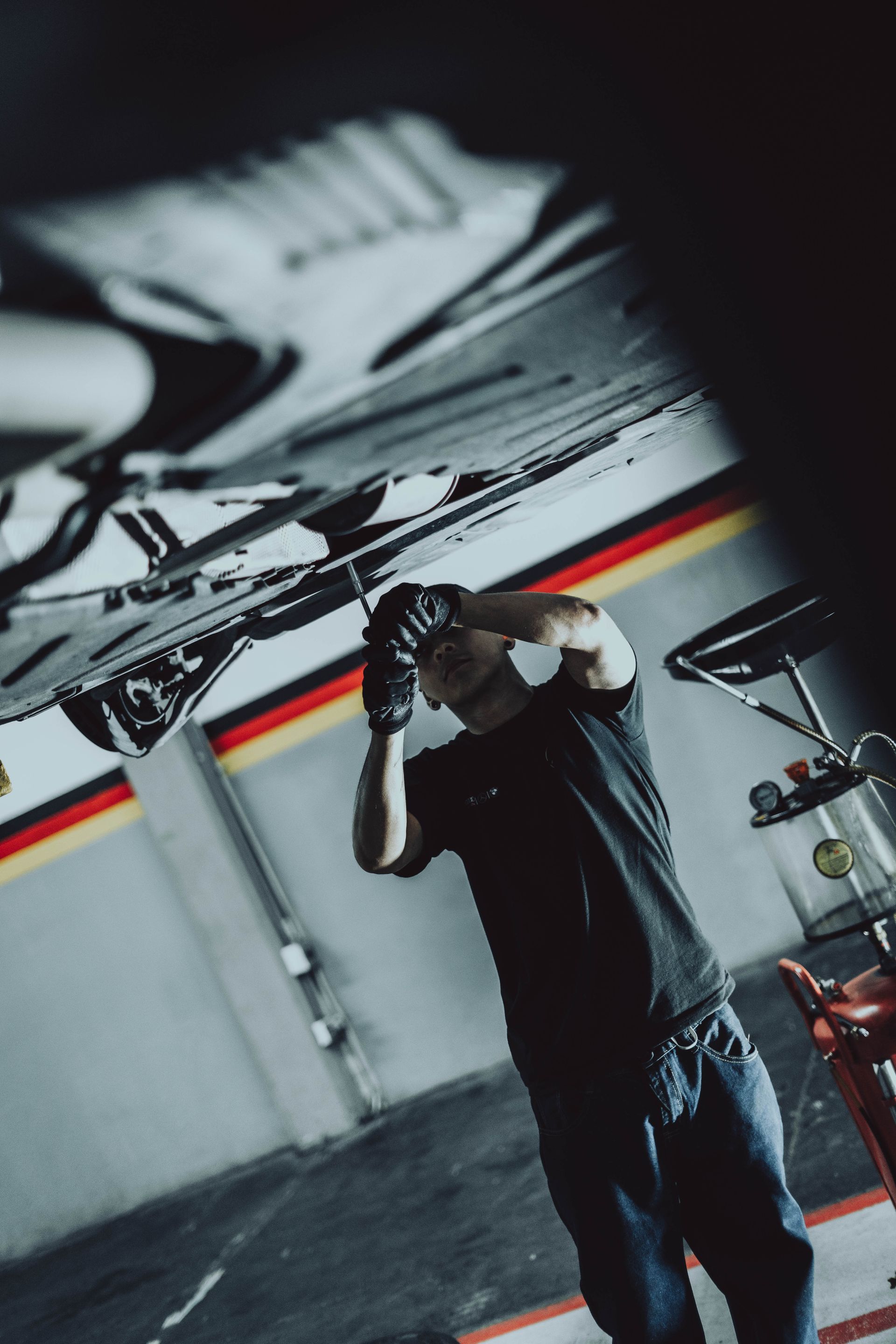 A man in a black shirt is working on a car in a garage.