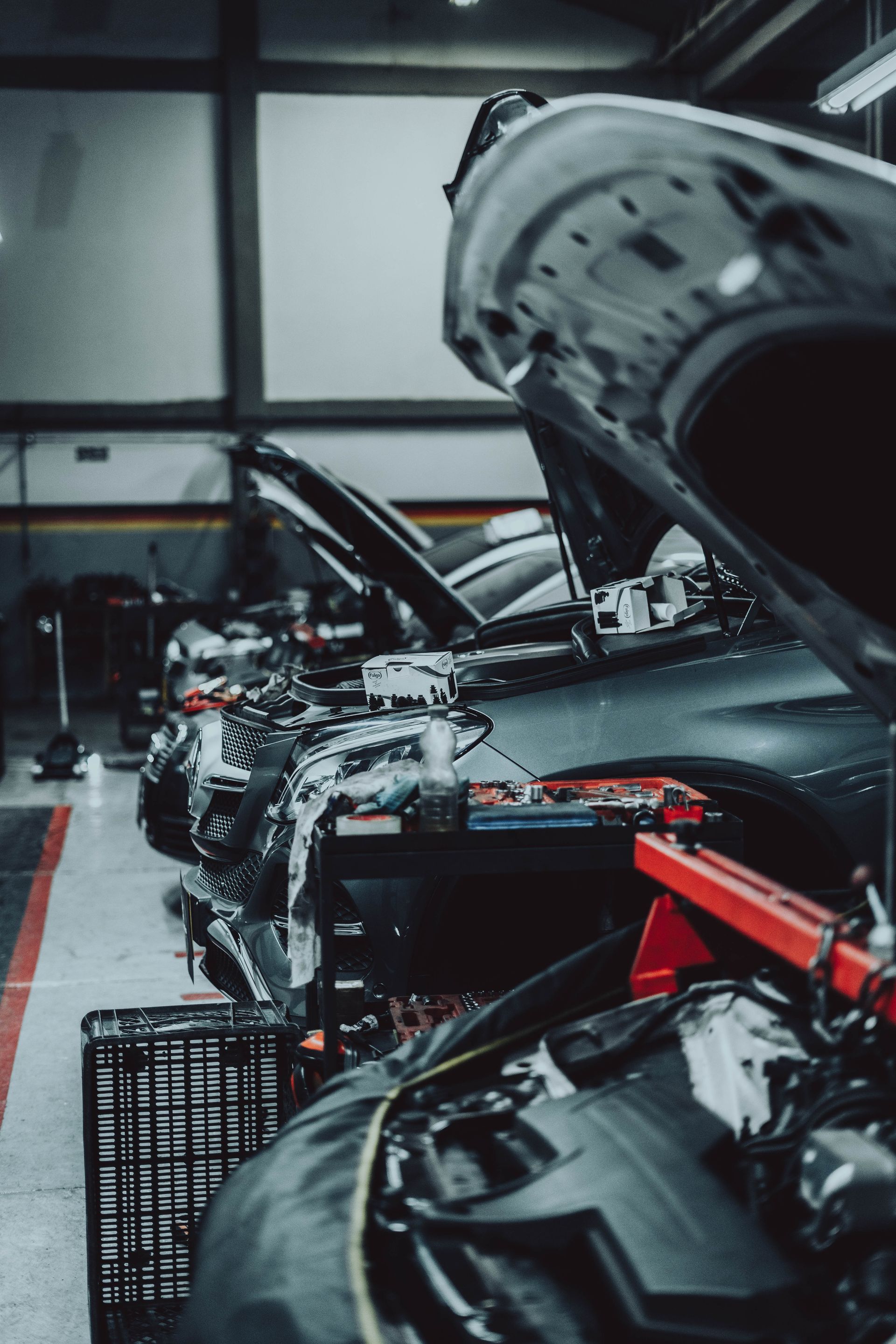A car is being worked on in a garage with the hood open.