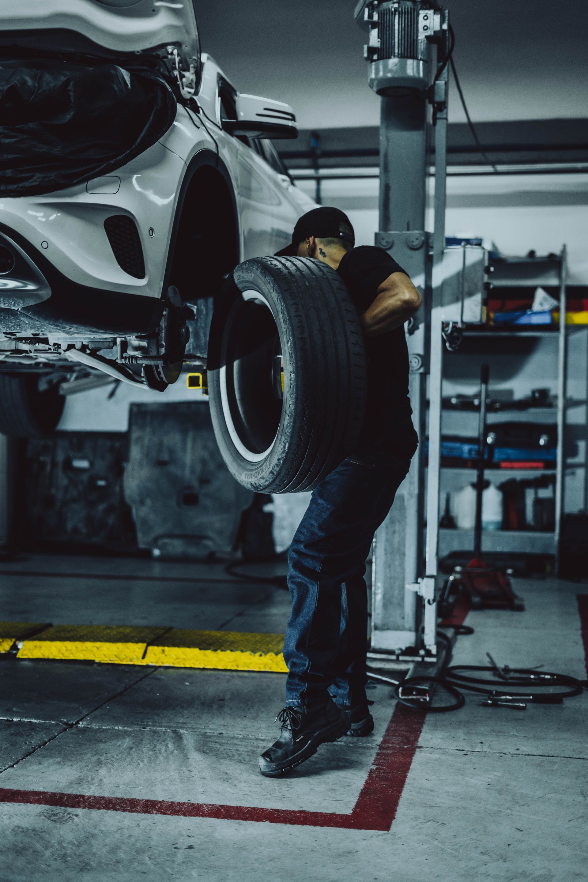 A man is changing a tire on a car in a garage.