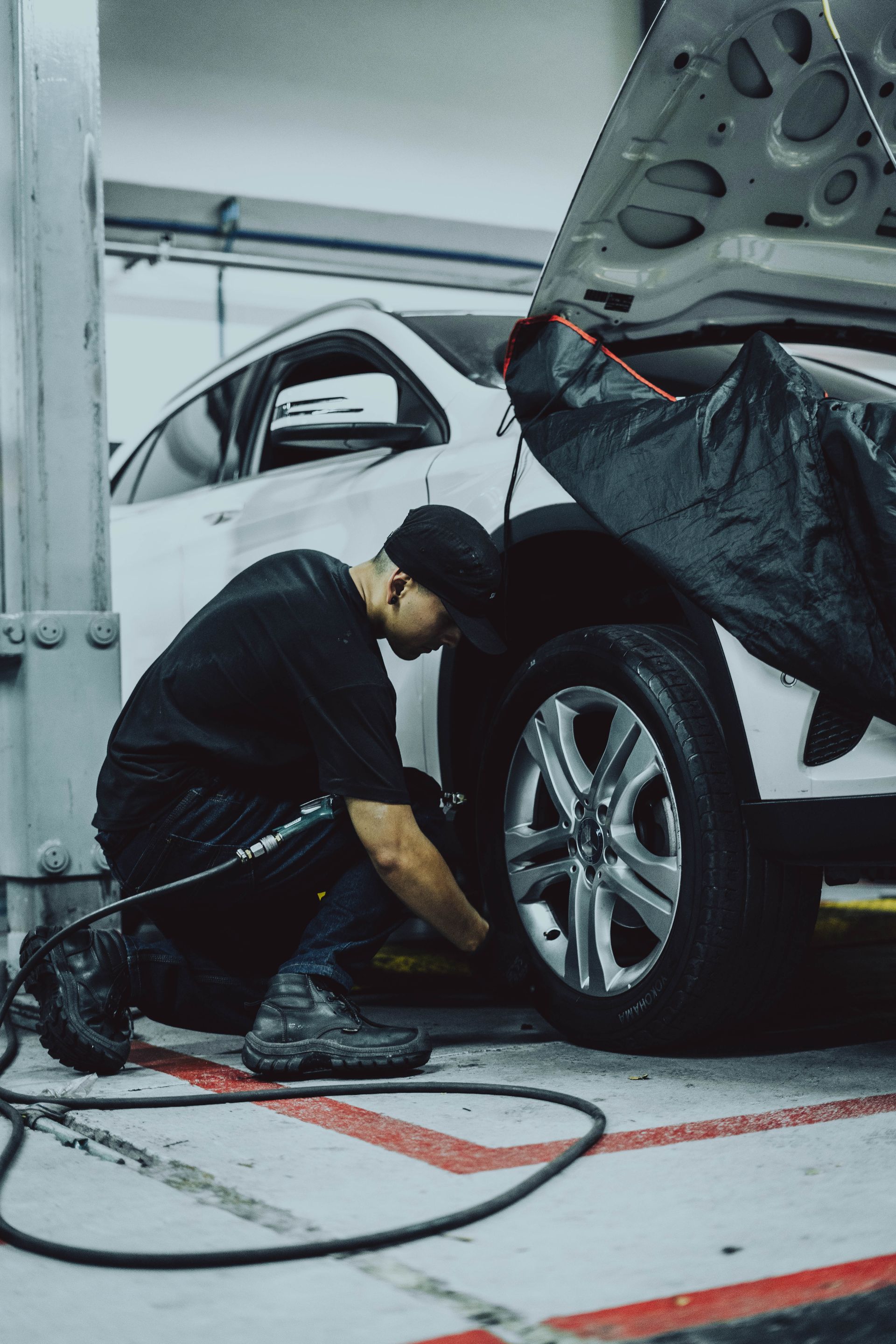 A man is changing a tire on a car in a garage.