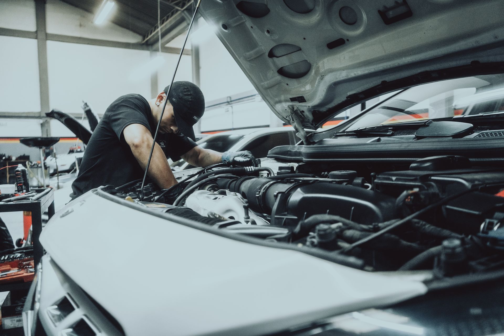 A man is working on the engine of a car in a garage.