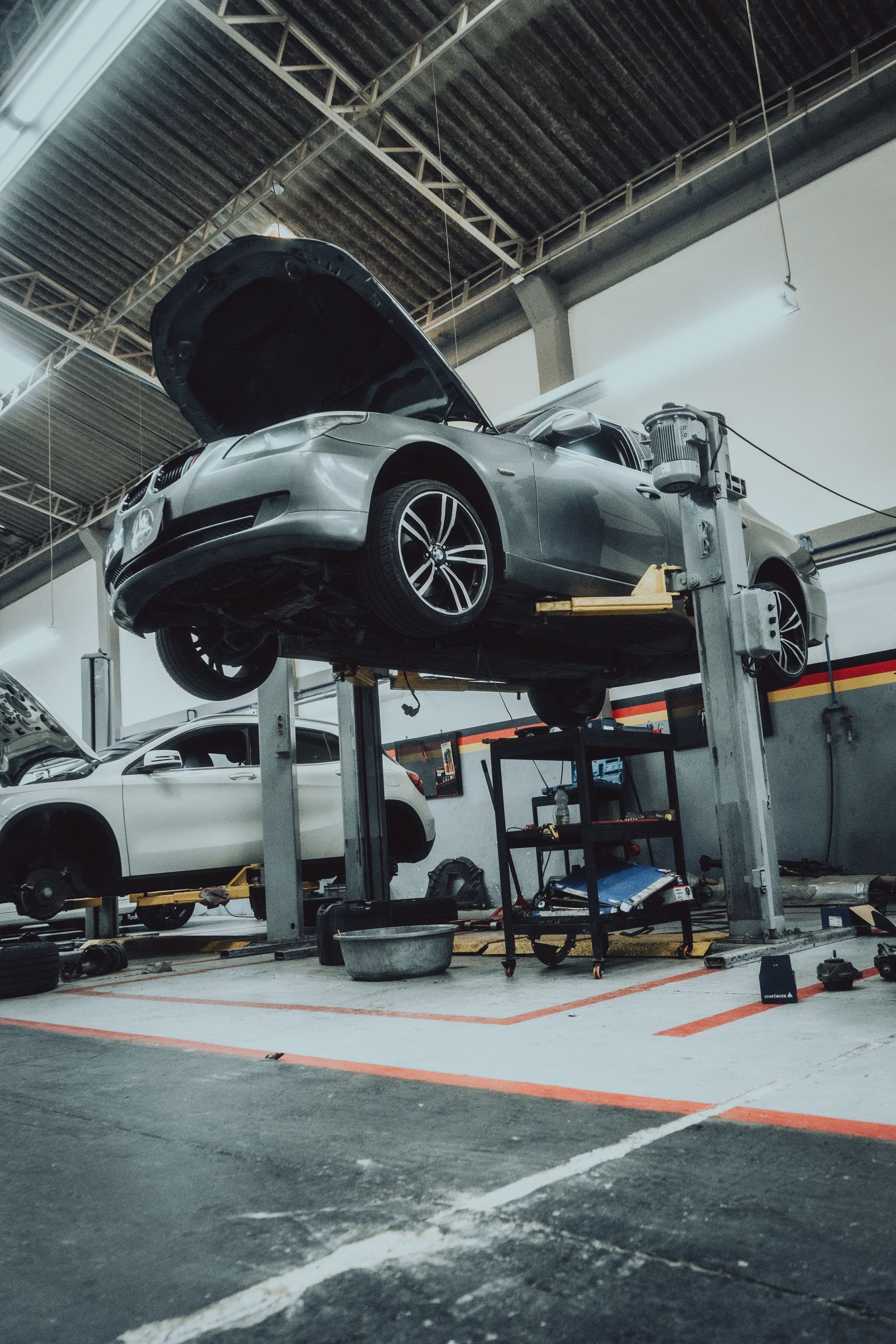 A car is sitting on a lift in a garage with its hood open.