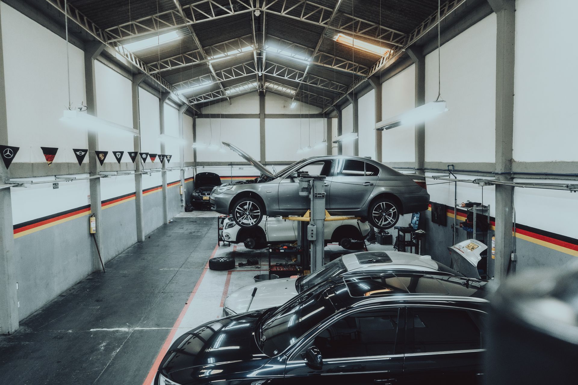 A row of cars are sitting on a lift in a garage.